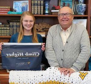 Chris Gilmer posing for a photo with Alexandrea Kile, who is holding the catamounts climb higher banner